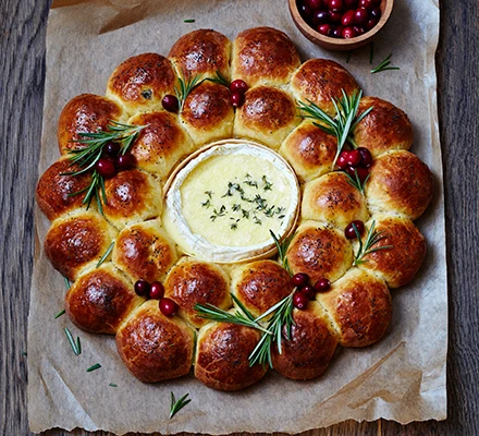 filled brioche rolls arranged in a wreath around a baked camembert