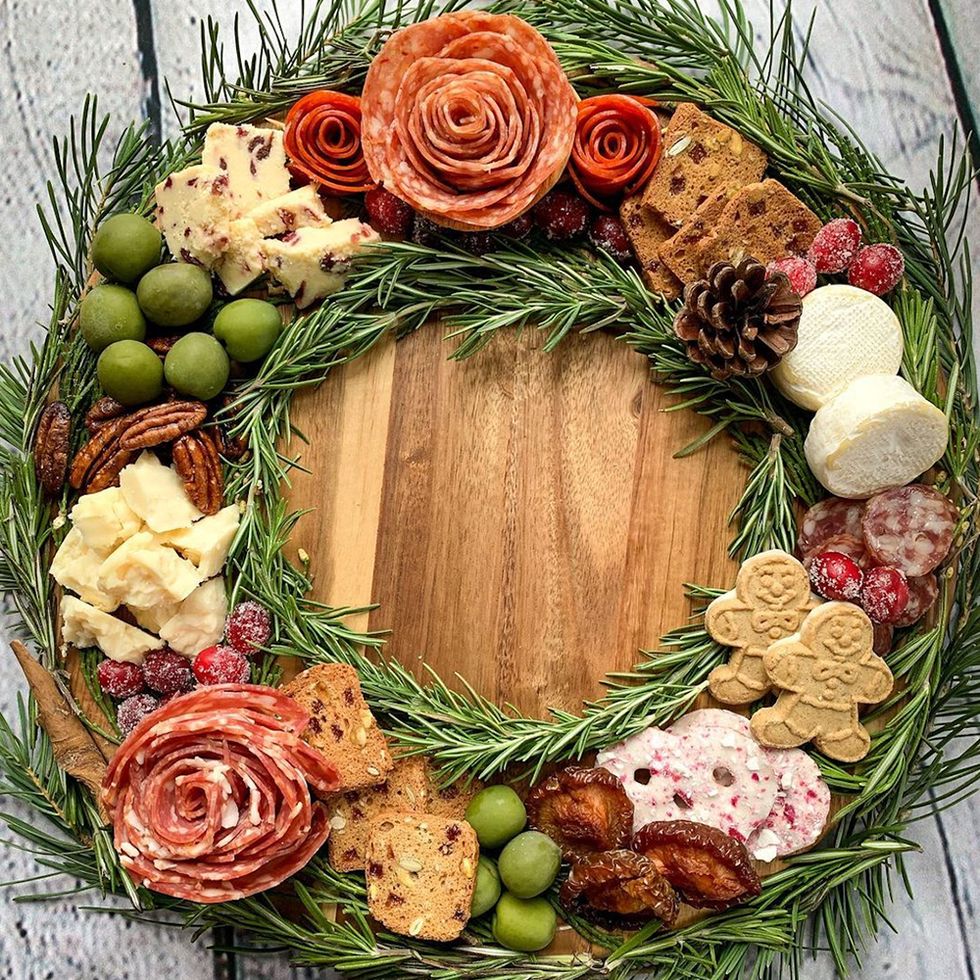 Charcuterie platter arranged in a the shape of a Christmas wreath with cheese, olives, sliced cured hams and peperoni